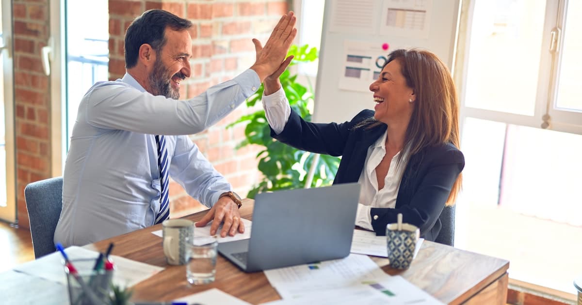 Two business professionals celebrating a successful IT consultant placement with a high-five